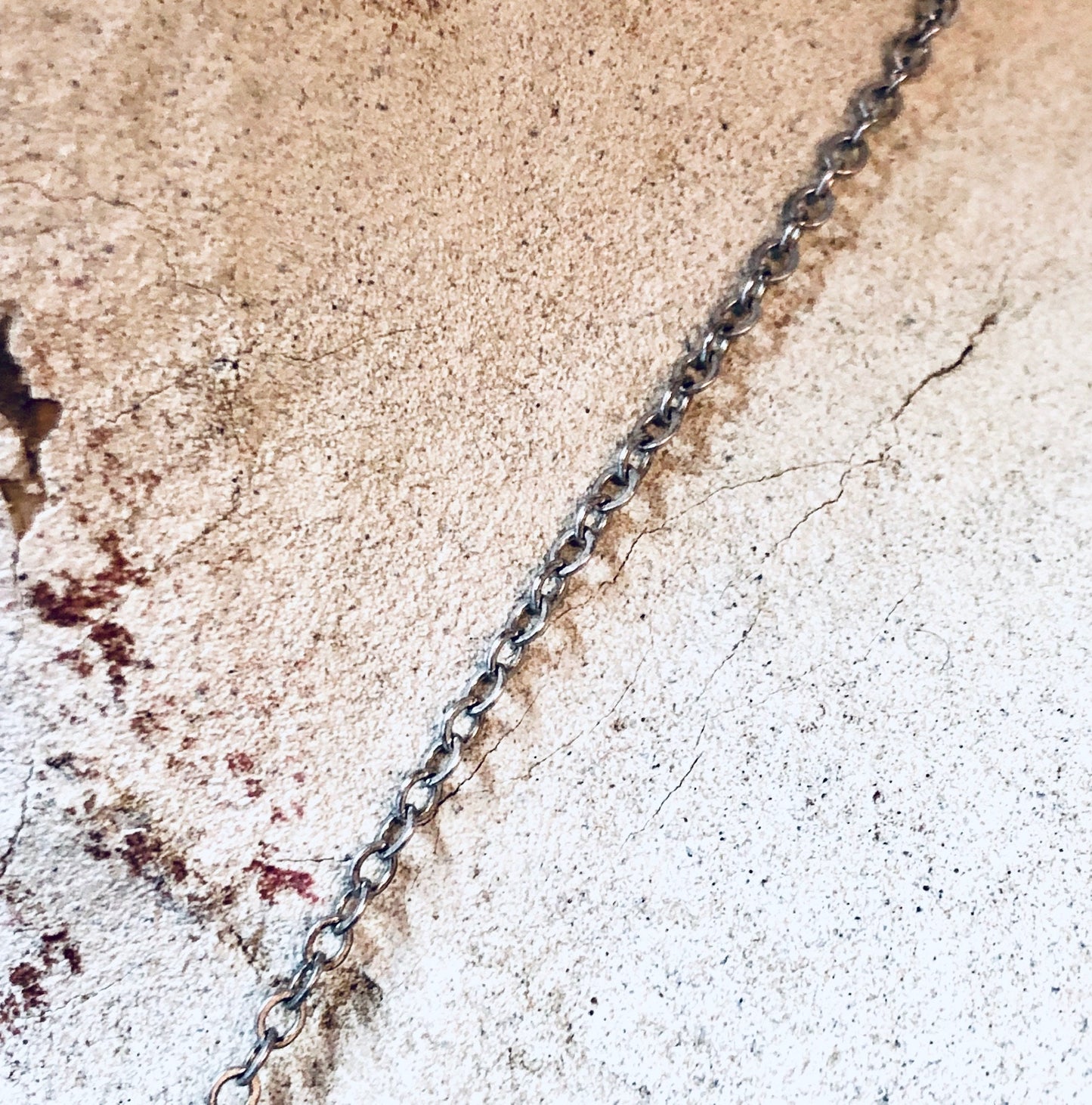 Vintage silver chain necklace on textured concrete surface