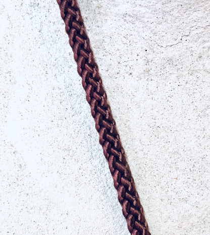 Braided brown and burgundy rope on white textured background, creating a vertical line down the center of the image.