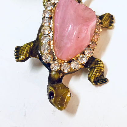 Vintage gold-toned turtle pin brooch with pink gemstone shell and rhinestone accents, animal jewelry from the past era