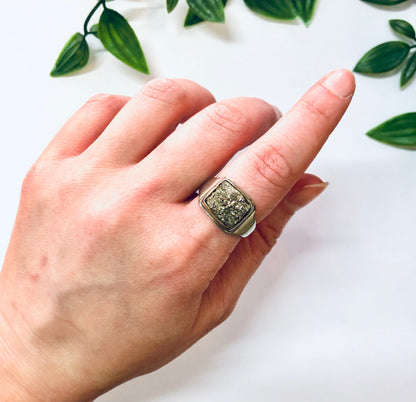 Vintage silver cocktail ring with raw quartz and fool's gold in a unique square design, set against green leaves.