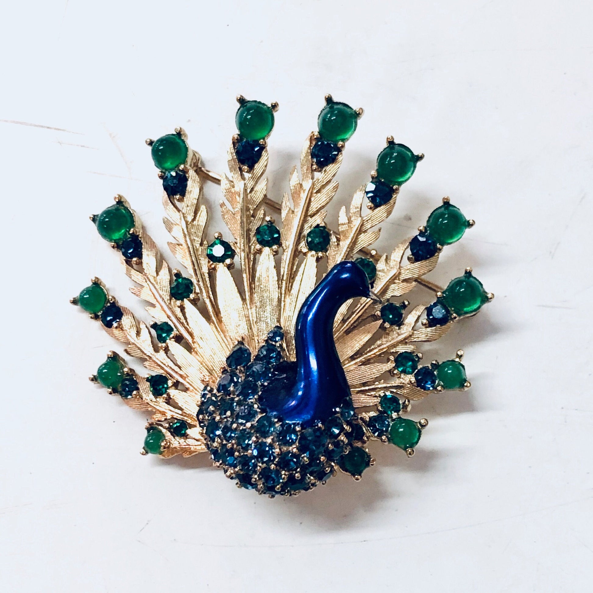 Boucher vintage peacock brooch pin featuring blue and green gemstones in a gold-toned setting, depicting a elegant peacock bird design.