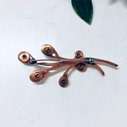 Vintage copper Matisse jewelry set featuring a brooch and hinged cuff bracelet with white enamel accents, displayed on a white background with a green leaf.