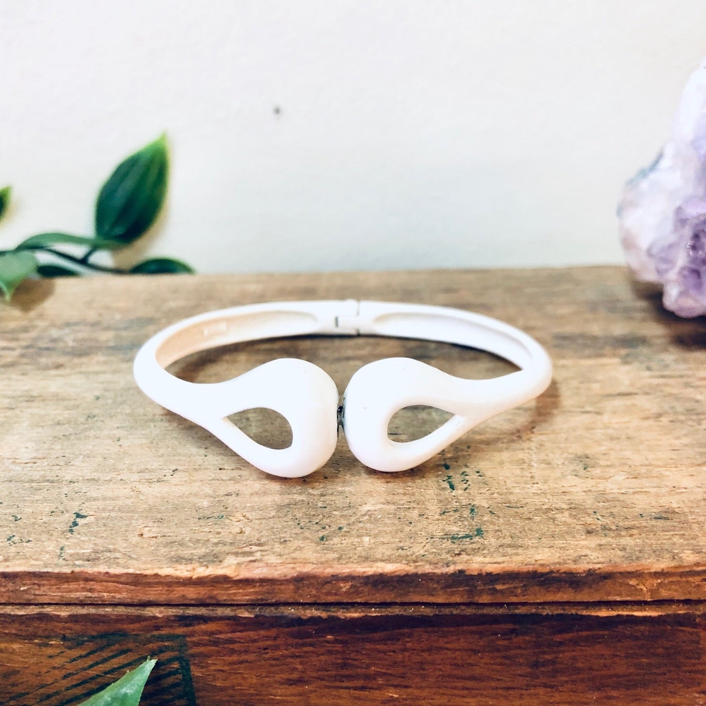 White Vendome cut out bangle bracelet on wooden surface with flowers