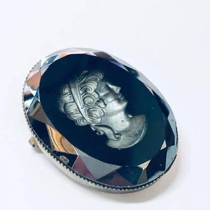 Vintage silver-toned cameo brooch featuring an etched female profile against a black background, accented with geometric shapes in shades of purple and peach.