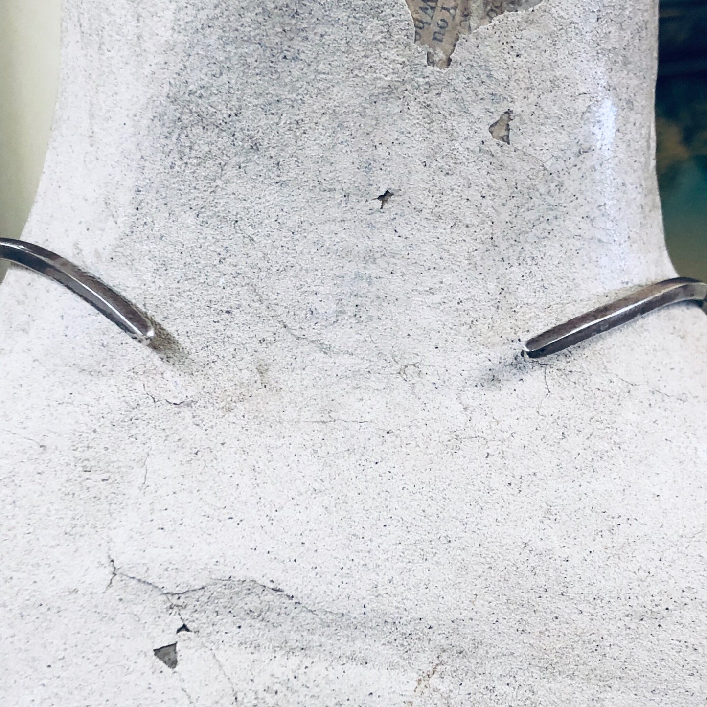 Closeup of rough grey concrete wall with metal rods protruding and small triangular metal pieces embedded in the surface.