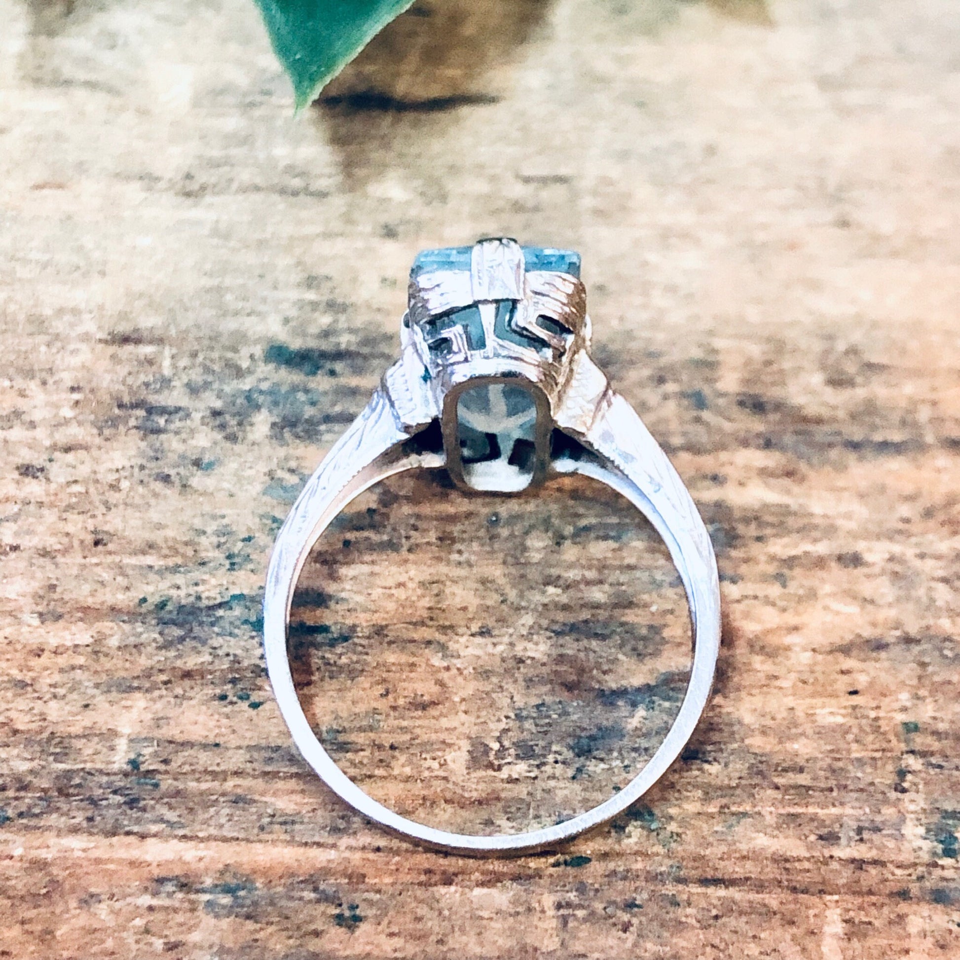 Vintage 18K white gold aquamarine engagement ring on rustic wooden surface