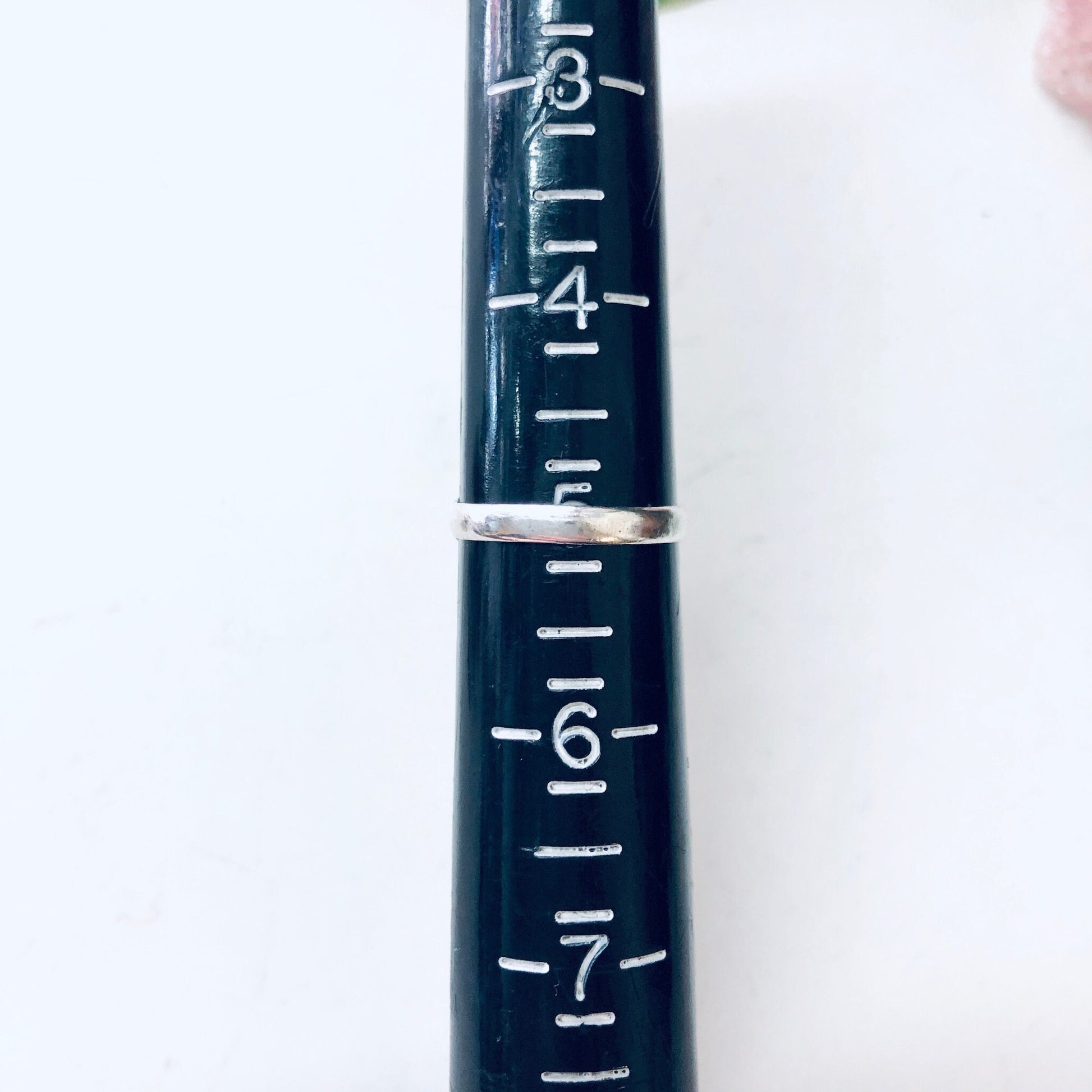 The image shows a close-up view of measurement markings on an old, dark blue metal ruler or measuring stick. The markings from 1 to 7 can be clearly seen etched in silver on the worn blue surface, indicating this is likely part of a vintage measuring tool.