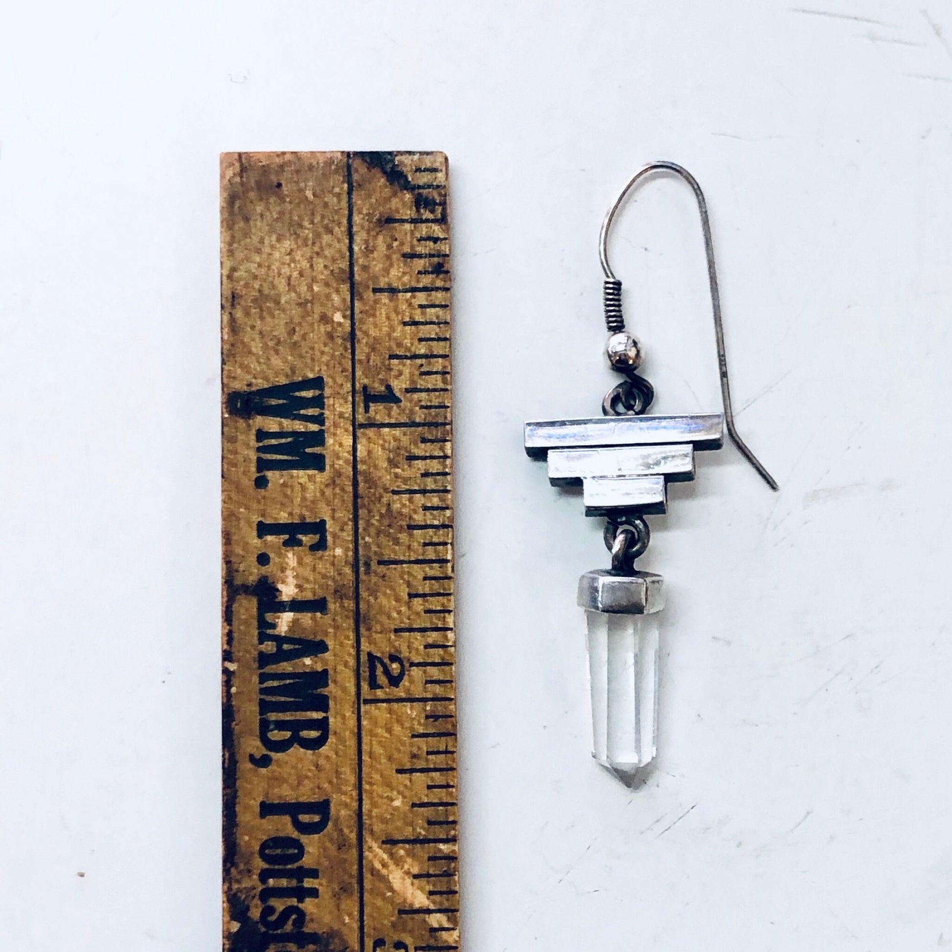 Vintage silver and quartz crystal dangle earrings next to old wooden ruler