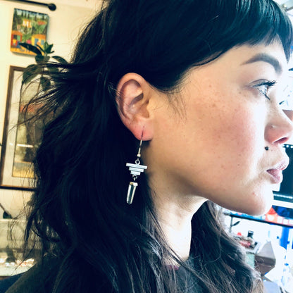 Woman wearing silver geometric dangle earrings with clear quartz crystals dangling from the ends, vintage statement jewelry for healing properties.