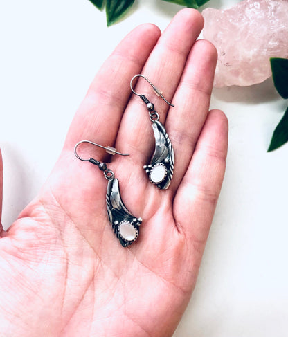 Vintage silver dangle earrings with mother of pearl inlays held in an open palm, showcasing bohemian southwestern style jewelry.