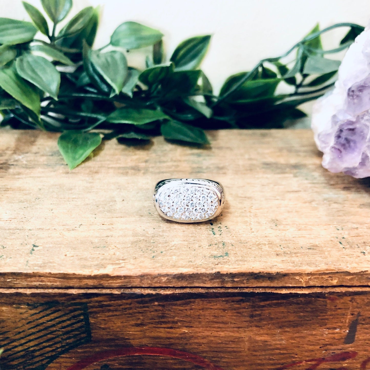 Vintage silver ring with faux diamond and rope design on wooden table with flowers in background