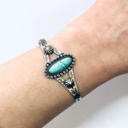 Vintage silver cuff bracelet with turquoise stone and stamped Southwestern design on a wrist