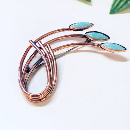 Vintage copper brooch with three turquoise blue stones, designed by Matisse Renoir. Unique costume jewelry piece featuring curved copper bands forming an abstract shape.