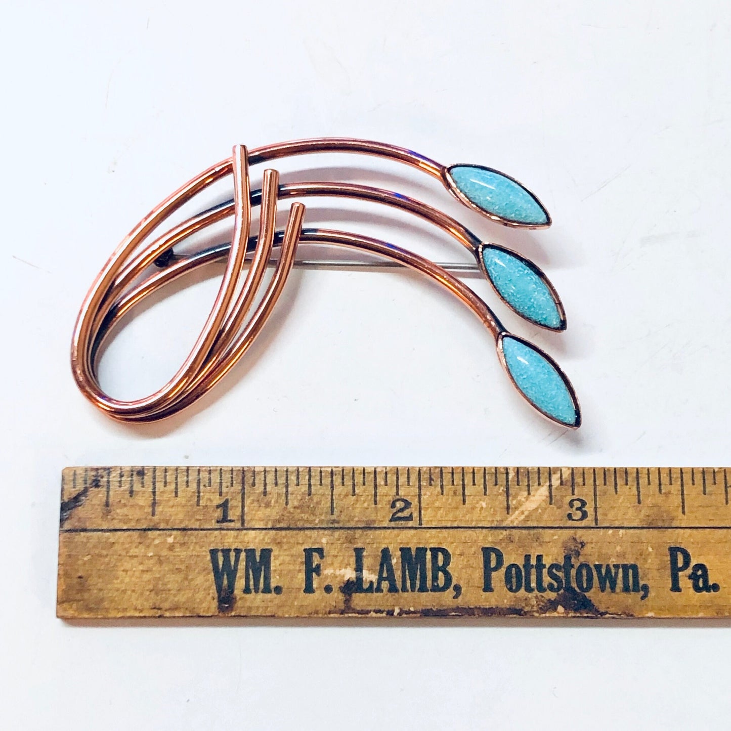 Vintage copper brooch with three elongated blue turquoise stones, resembling a Matisse or Renoir design, shown with ruler for scale.