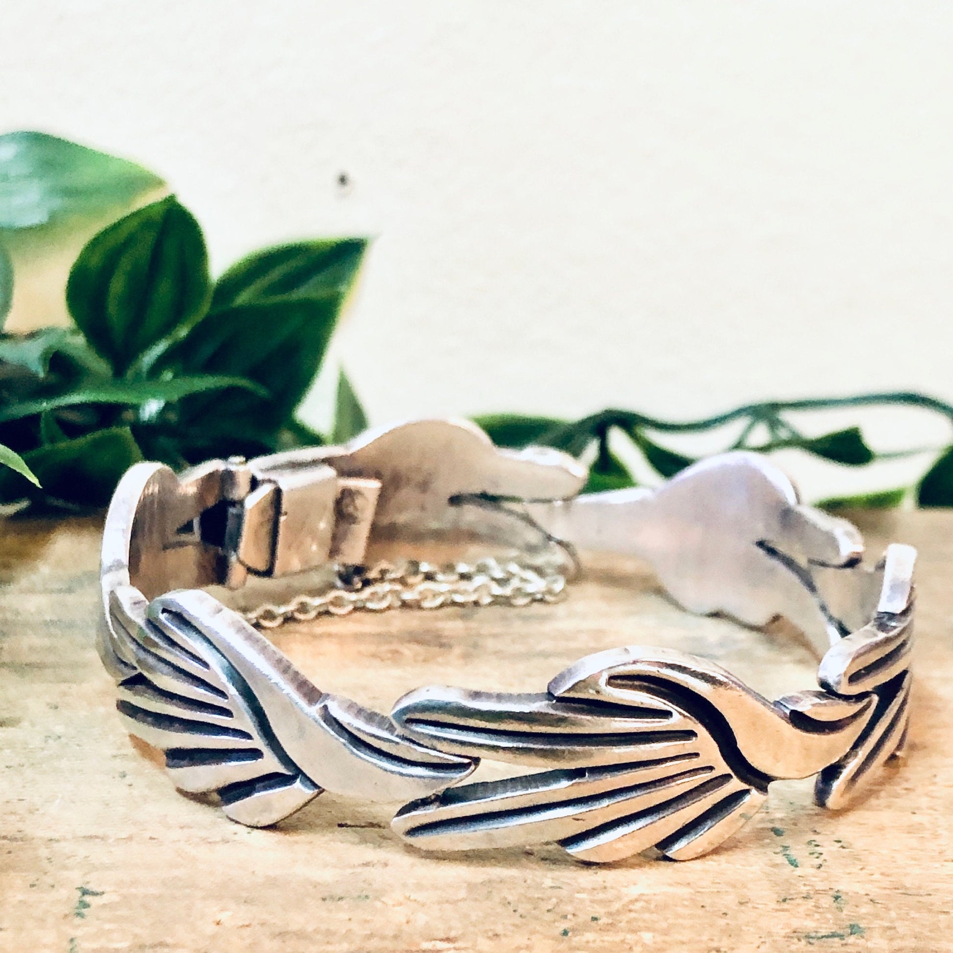 Vintage Taxco sterling silver modernist link bracelet by J. Flores, featuring an organic wave-like design, displayed with greenery in the background.