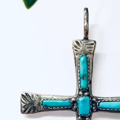 Vintage Zuni silver cross pendant with turquoise inlay on a white background