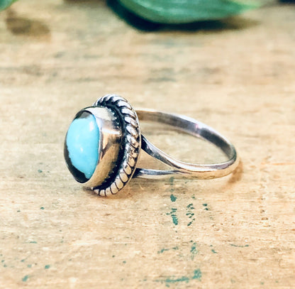 Vintage silver ring with blue turquoise cabochon stone on textured wooden surface