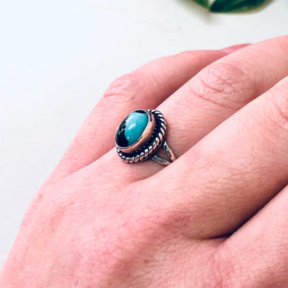 Vintage silver ring with oval blue cabochon stone set in a twisted rope bezel on a hand, showing intricate southwestern style design and craftsmanship of the 925 sterling silver jewelry piece.