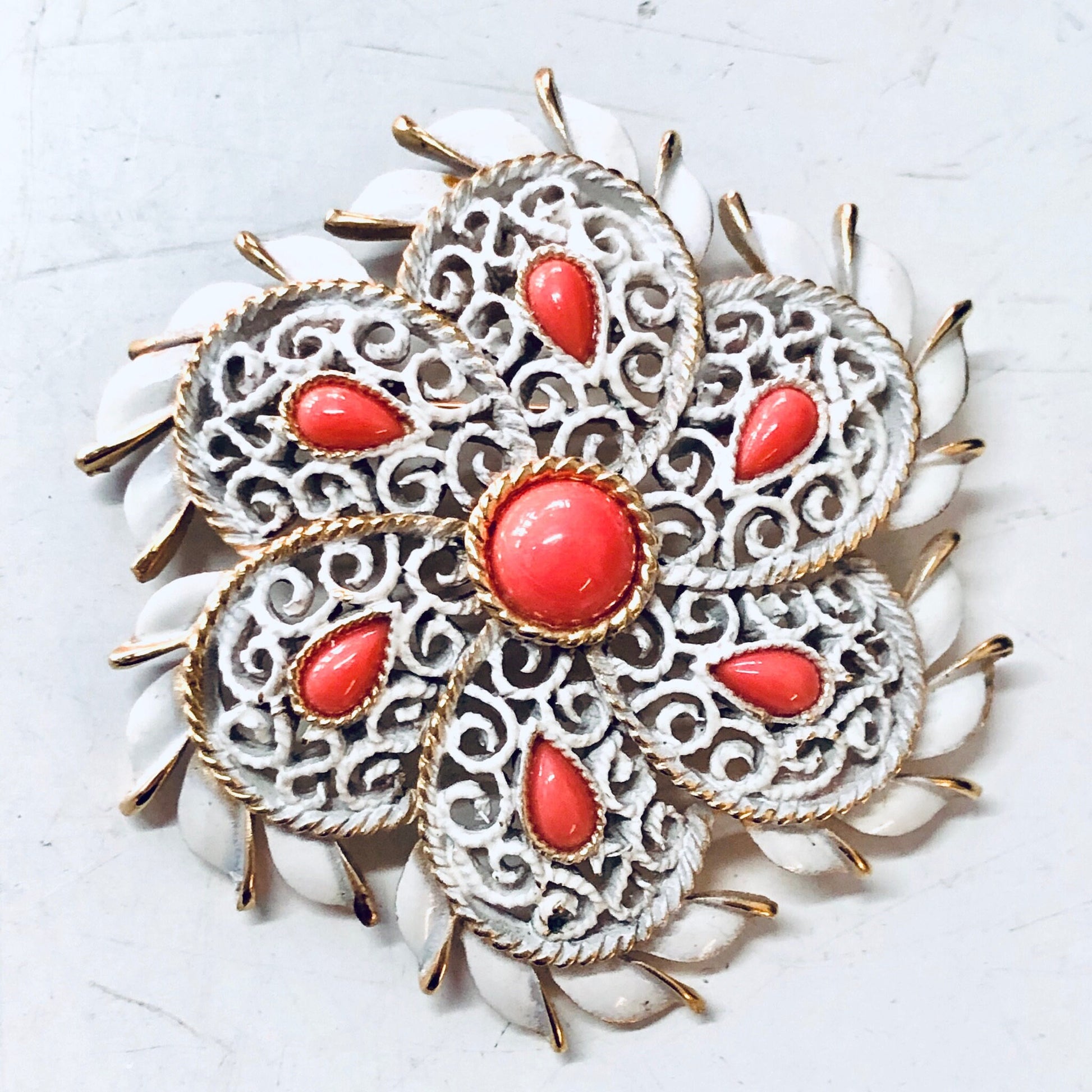 Vintage Trifari white enamel brooch with orange cabochons and gold tone accents in an ornate floral design, a striking statement jewelry piece from a renowned vintage brand.