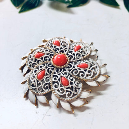 Vintage Trifari white and orange brooch with gold-toned accents and intricate filigree design, featuring a round shape and statement style.