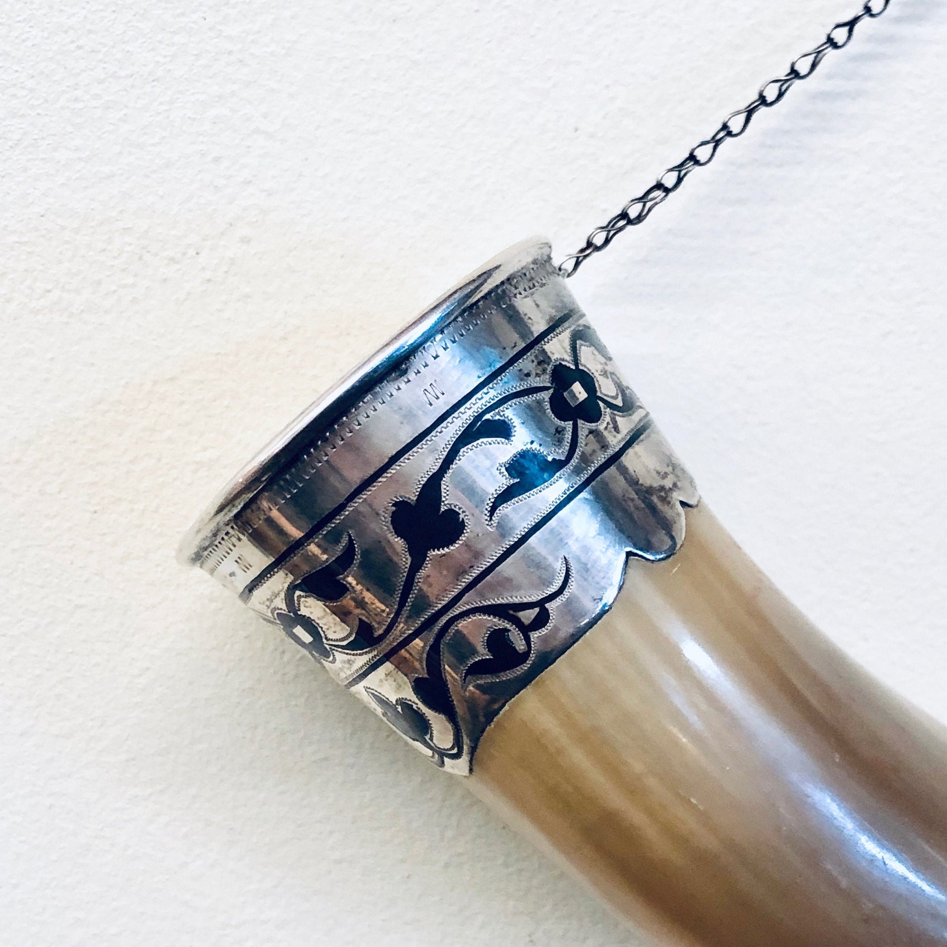 Vintage decorative horn cup with silver accents hanging from chain, unique wall decor piece