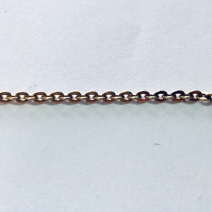 Gold chain with small, round links against a plain background