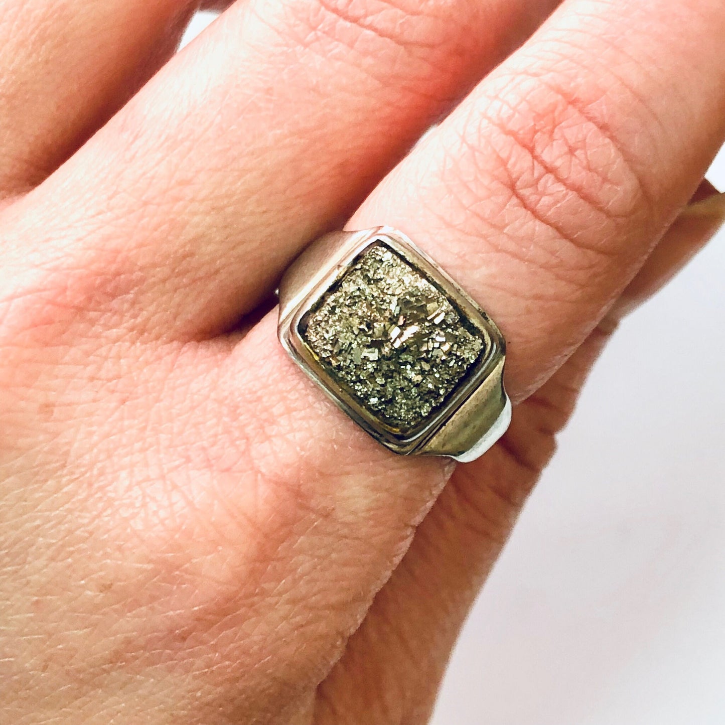 Vintage silver cocktail ring featuring raw quartz stone with golden flecks set in square sterling silver frame, shown on person's finger.