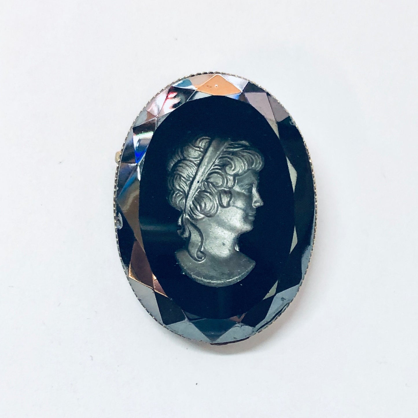 Vintage black cameo brooch featuring an etched silver-toned profile portrait set in a faceted blue gemstone frame.