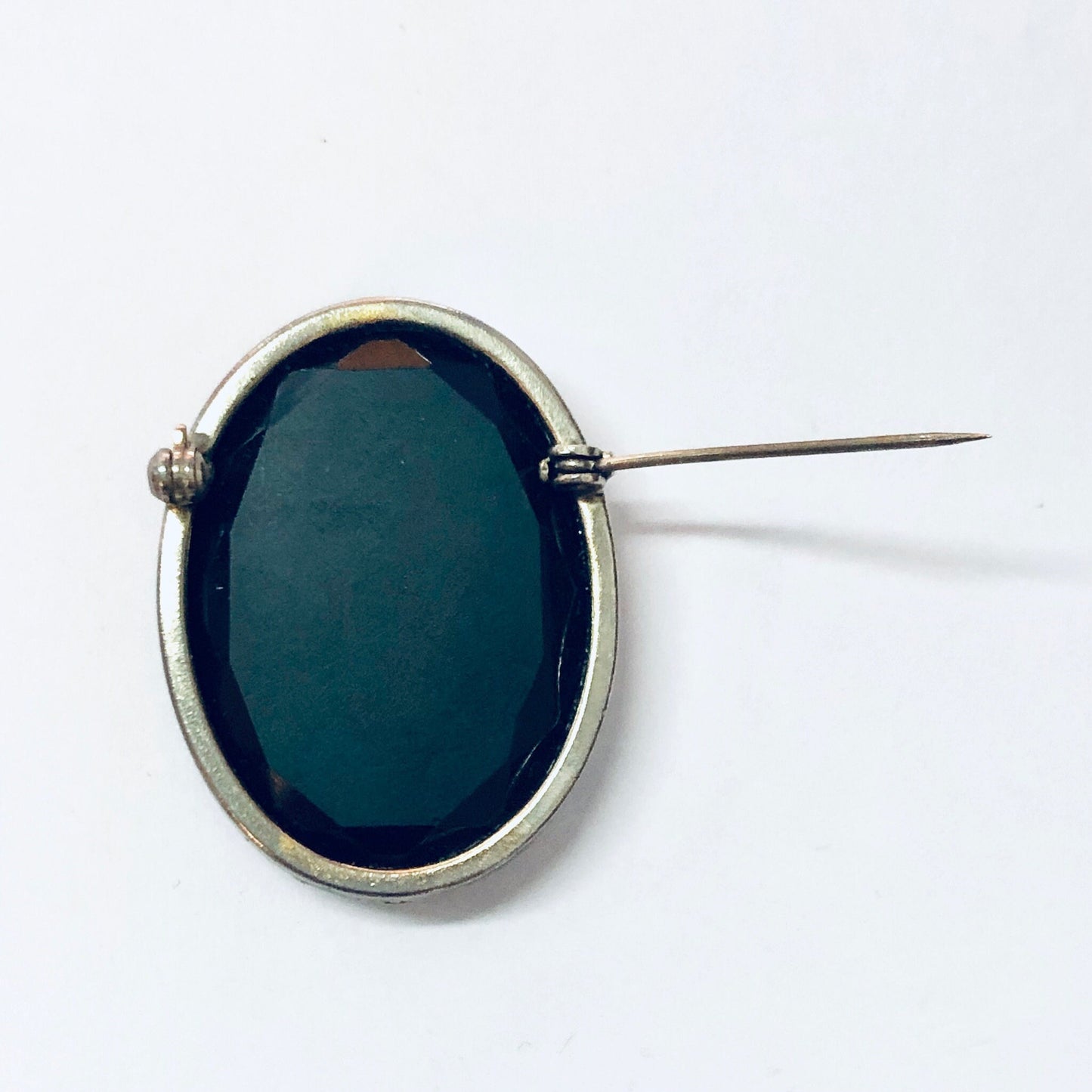 Vintage silver-toned cameo brooch with black etched glass stone and pin closure against white background