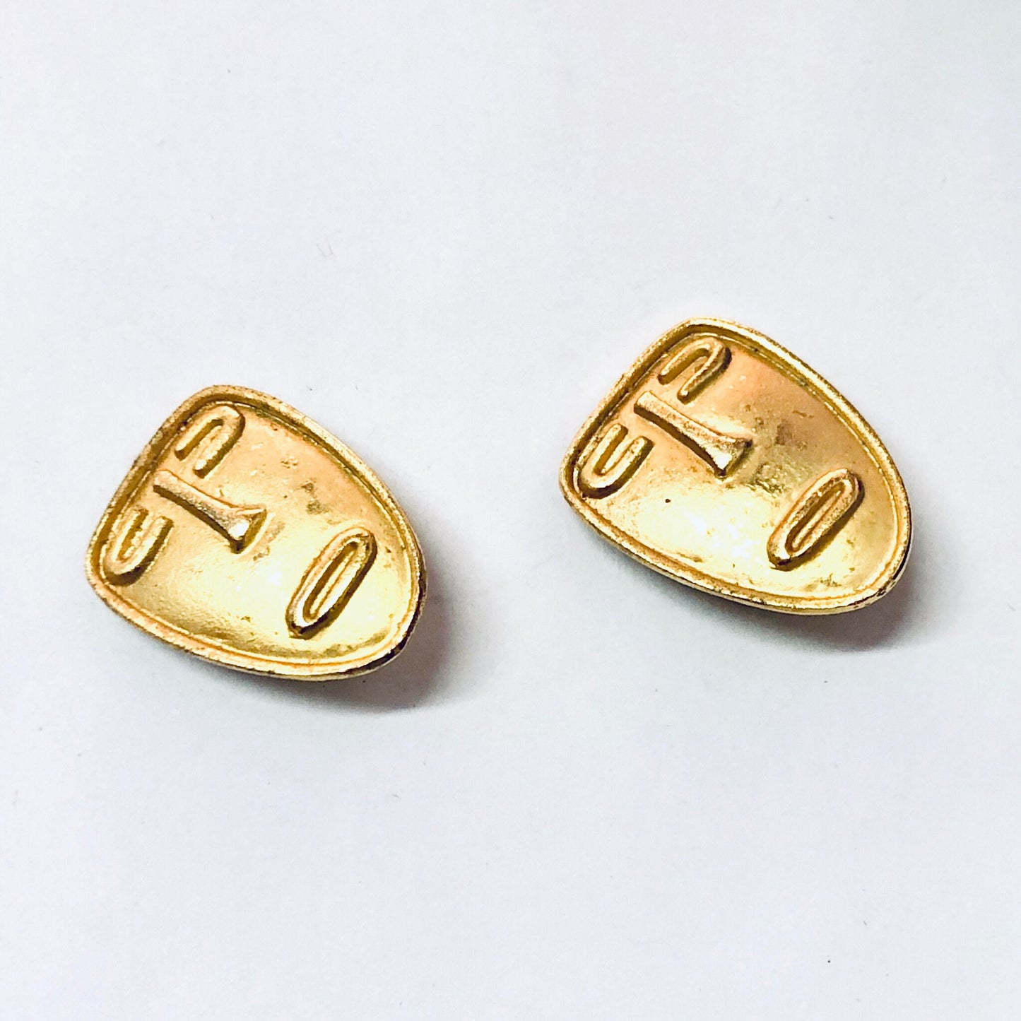 Vintage gold tone abstract face clip-on earrings, unique mask-shaped jewelry from the 1980s era.