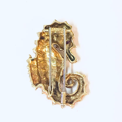 18K yellow gold and platinum vintage David Webb seahorse brooch from the 1970s, featuring a ruby eye. Intricate metal work forms the detailed seahorse shape of this statement piece pin.