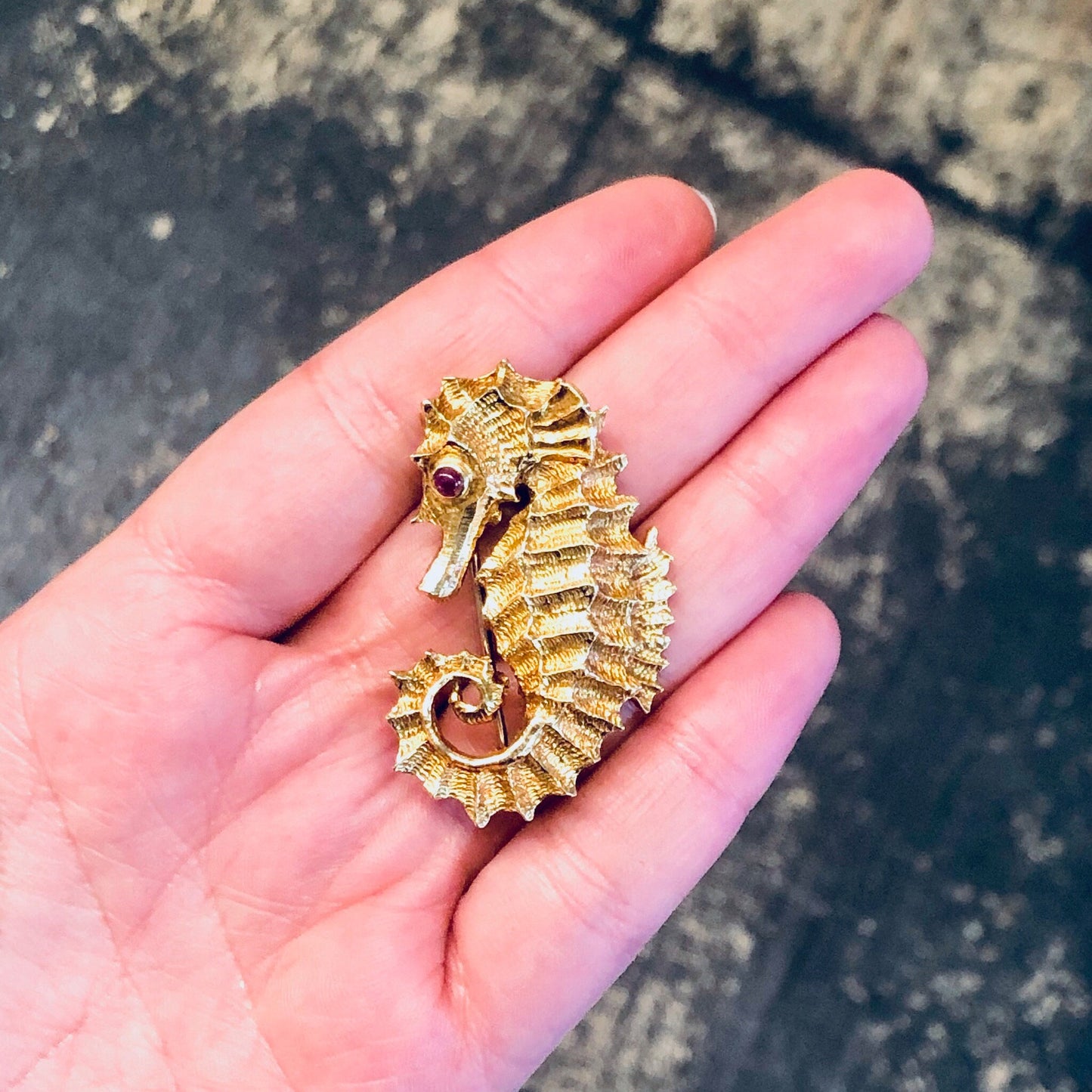 18K gold and platinum vintage David Webb seahorse brooch from the 1970s with ruby eye, held in palm of hand