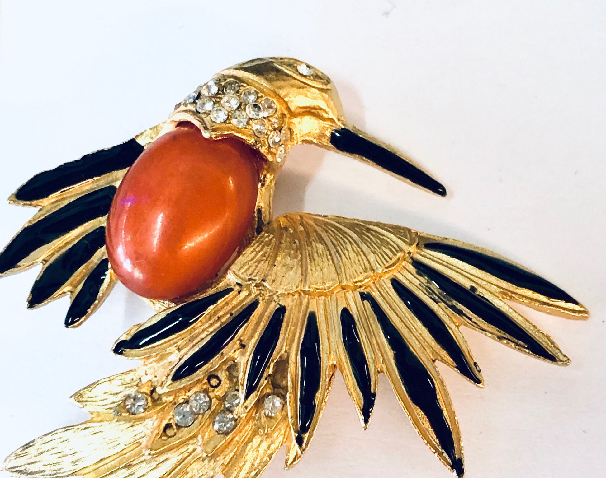 Vintage gold-toned bird brooch with orange stone, black enamel accents, and rhinestone details, a unique piece of vintage jewelry.