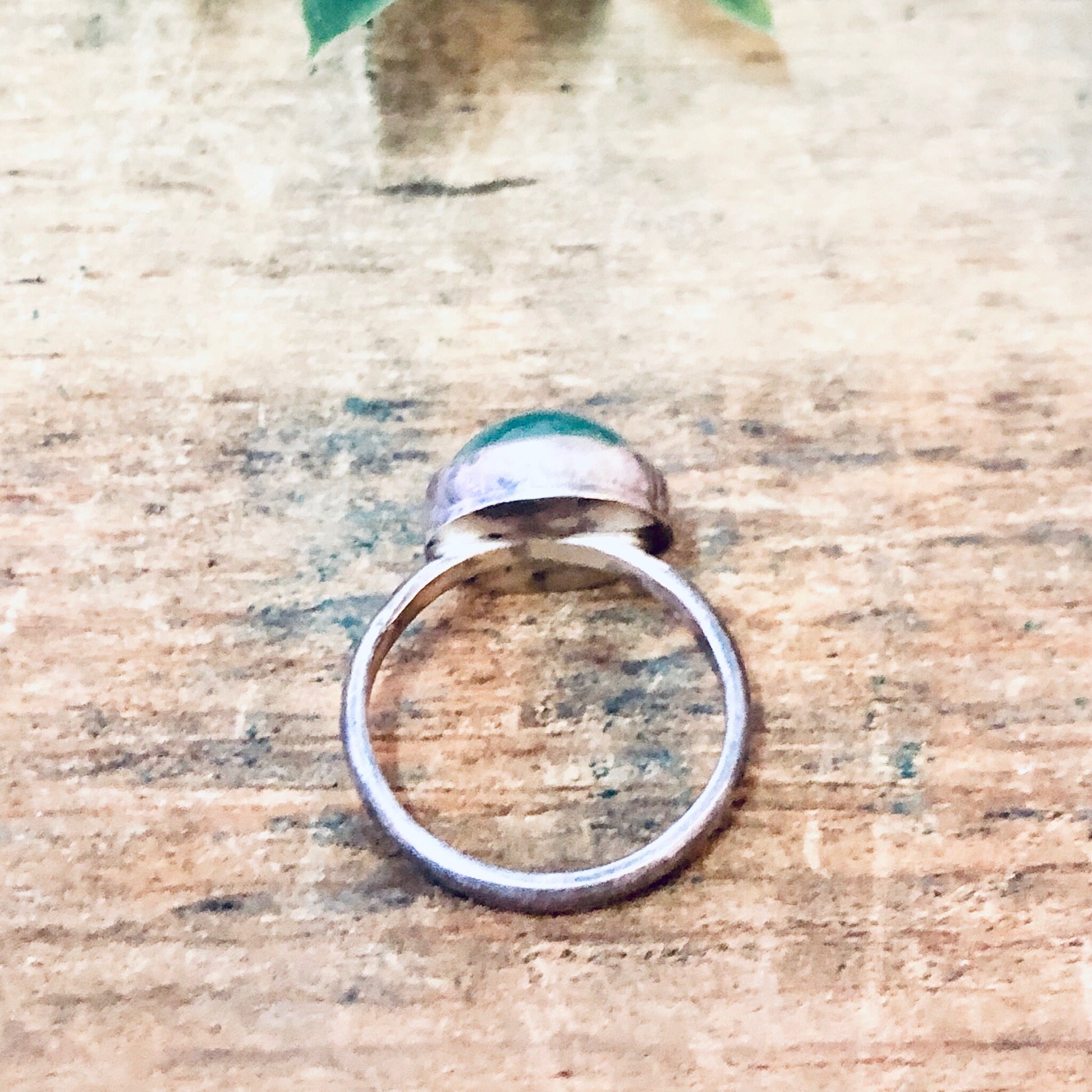 Vintage silver ring with round green cabochon gemstone on weathered wood surface