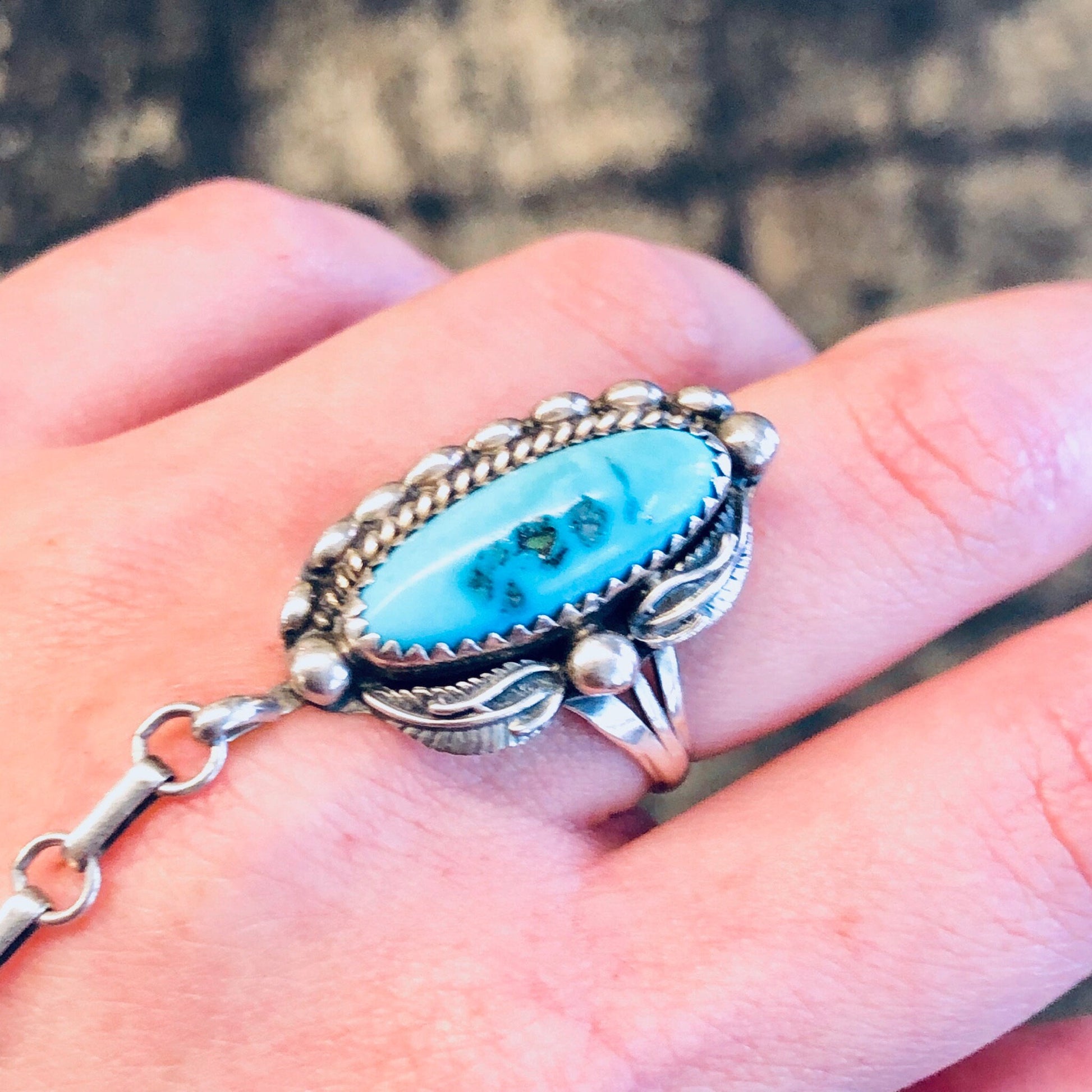 Vintage Navajo turquoise slave bracelet with silver accents, bohemian style jewelry on hand against blurred background