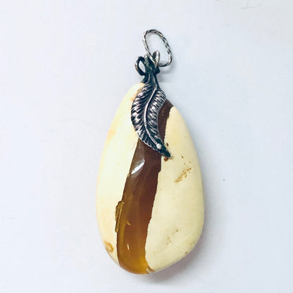 Vintage butterscotch amber pendant in silver setting, showing yellow and milky tones, against a white background.