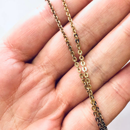 Gold cable link chain necklace held in person's hand