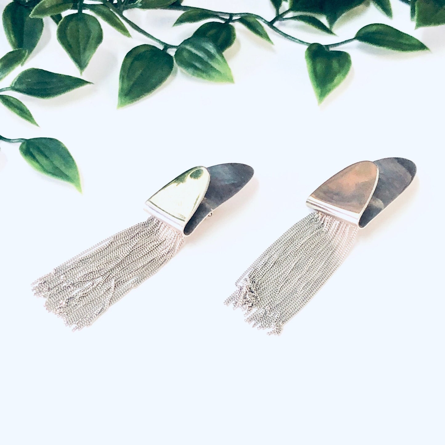 Vintage silver clip-on fringe earrings with unique design, made in Italy from 925 sterling silver, shown on white background with green leaves.