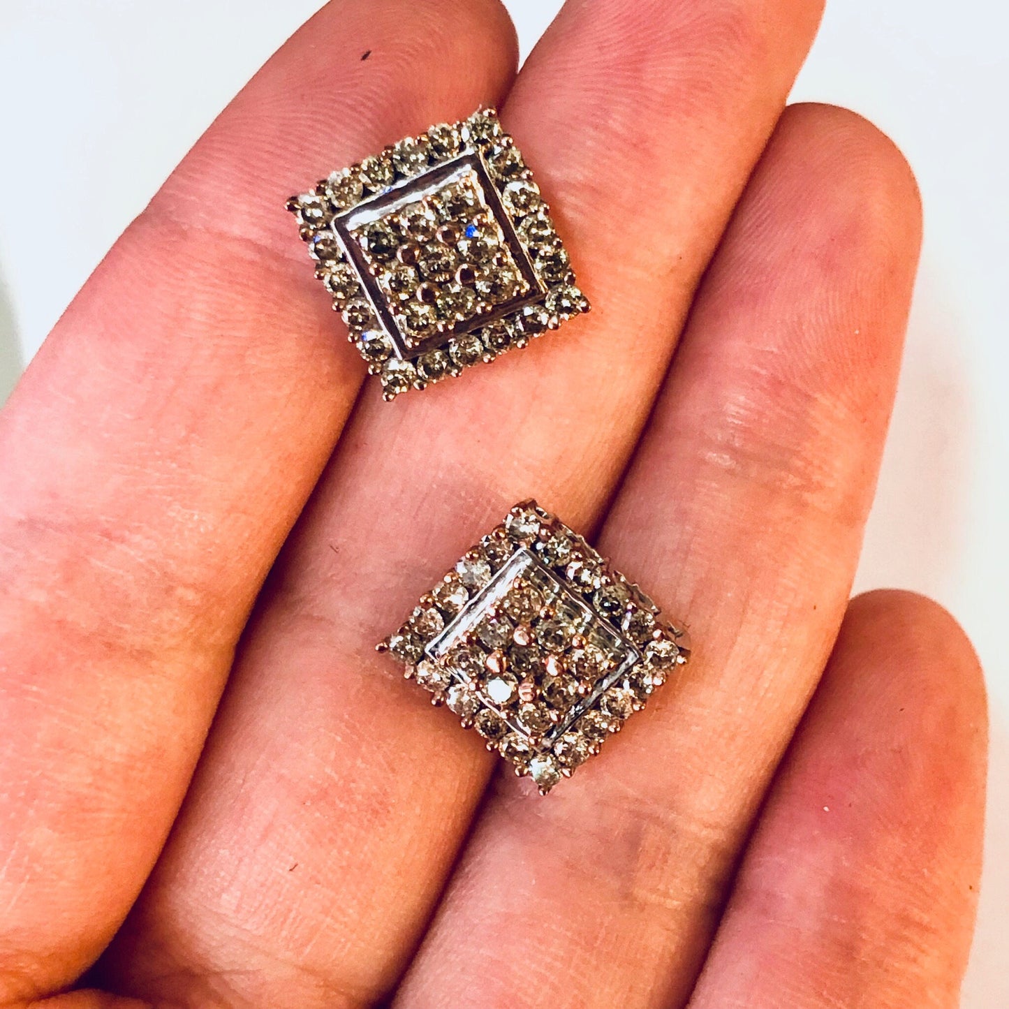 Vintage diamond cluster earrings set in 10K gold featuring an Art Deco-inspired square design with intricate diamond patterns, held in a hand to show scale and detail.