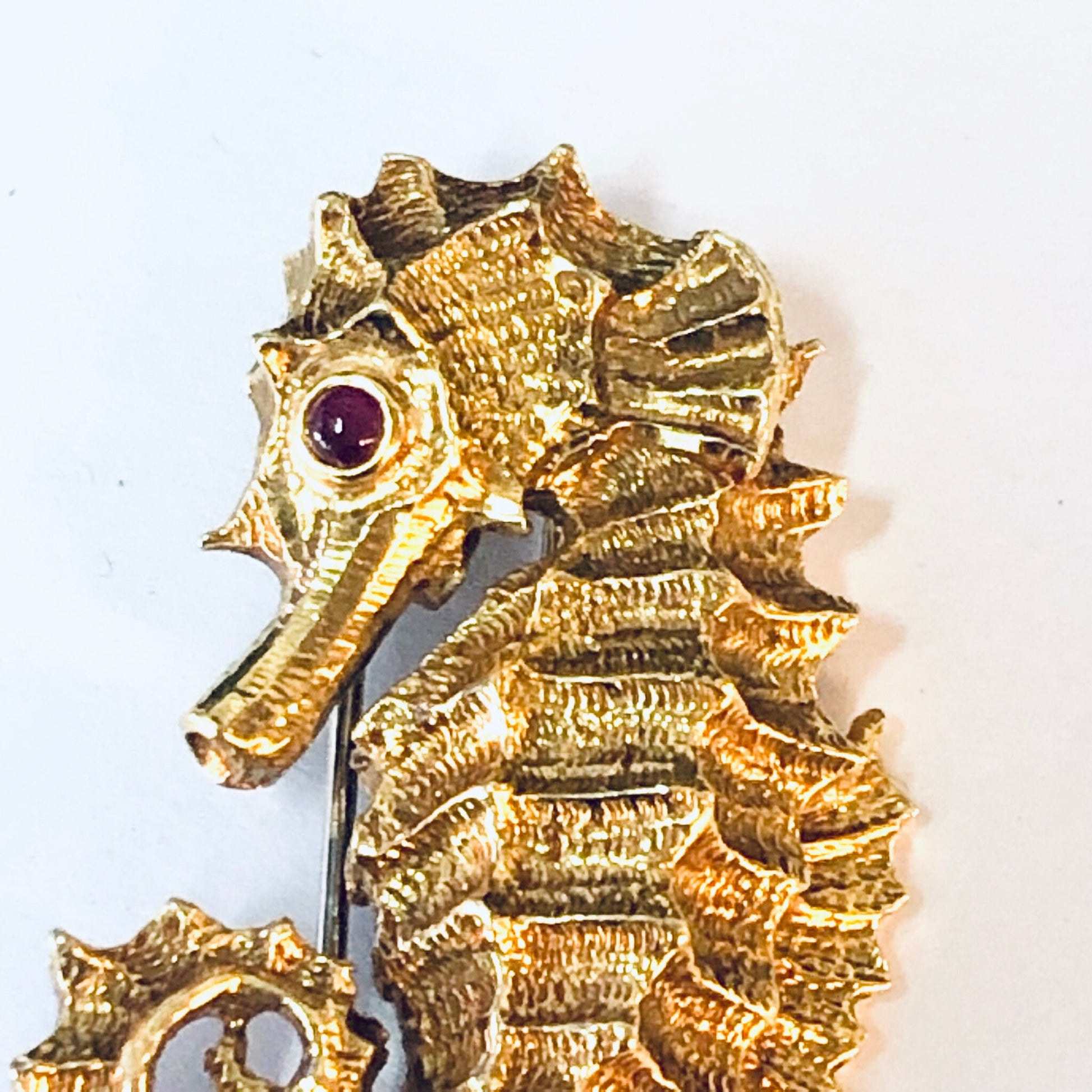 18K yellow gold and platinum vintage David Webb seahorse brooch from the 1970s, featuring intricate textured details and a ruby eye accent.