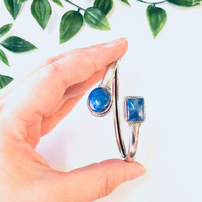 Vintage silver bangle bracelet with blue lapis lazuli gemstones held in a hand with green leaves in the background