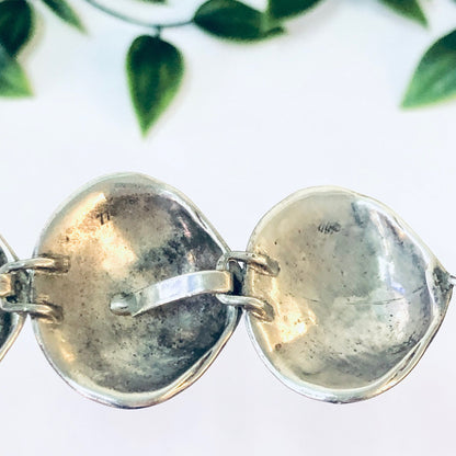 Vintage silver link bracelet with unique shell design, 925 sterling silver, small size, close-up view with green leaves in soft focus background