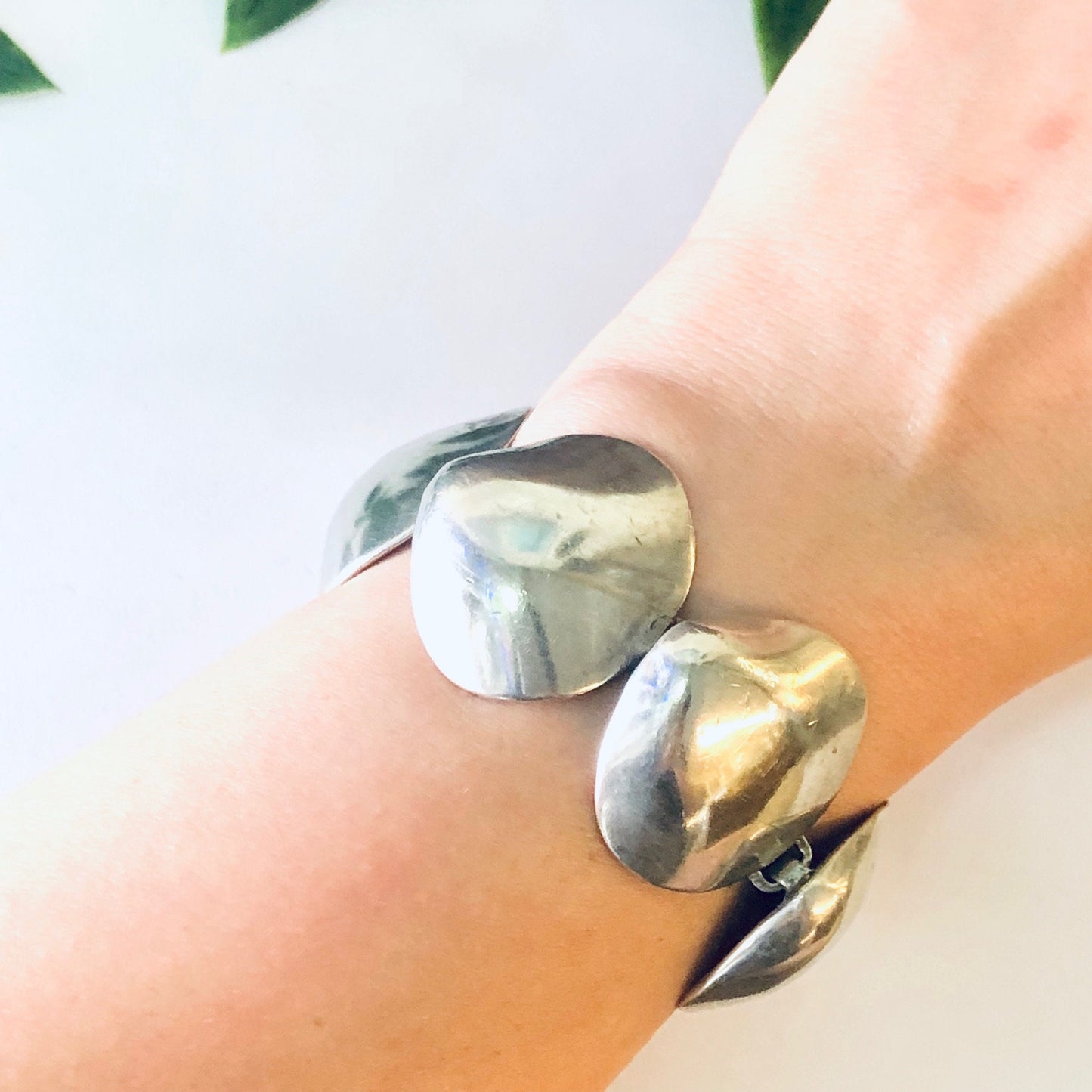 Vintage silver link bracelet with unique shell design, 925 sterling silver, small size, close-up on wrist with green leaves in background