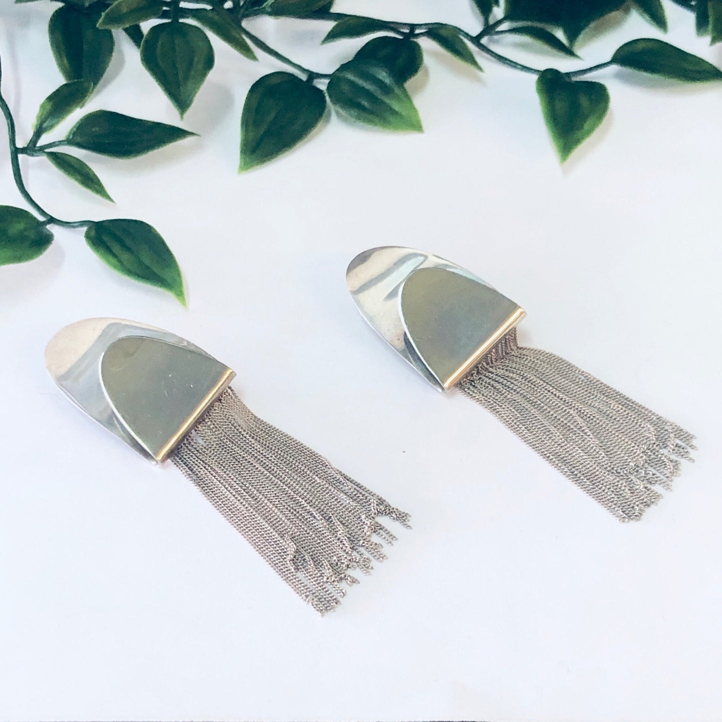 Vintage silver fringe clip-on earrings with unique design, made in Italy from 925 sterling silver, displayed on white background with green leaves.