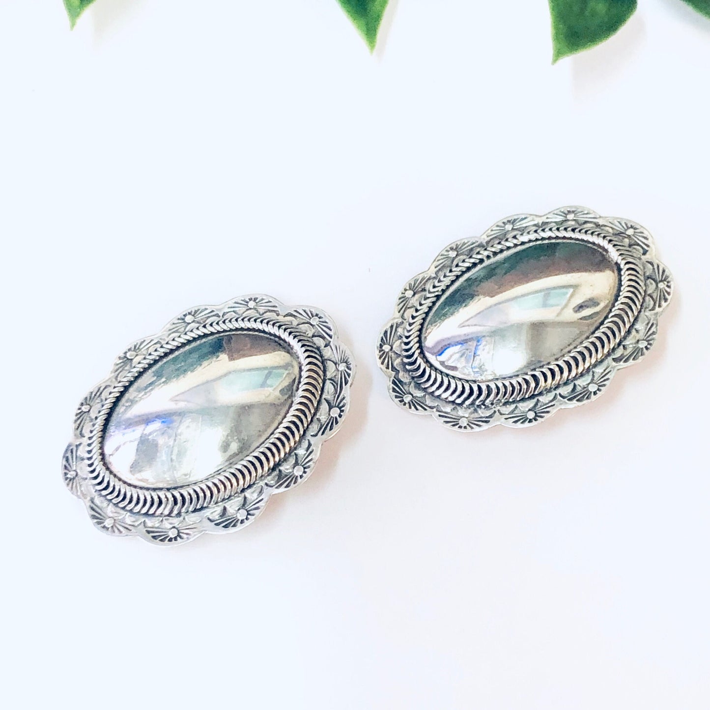 Vintage silver concho clip-on earrings with ornate engraved details, showcasing unique Taxco 925 sterling silver jewelry craftsmanship.