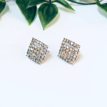 Vintage 10K gold diamond cluster stud earrings with square Art Deco style design on white background with green leaves