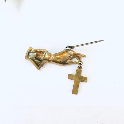 Vintage gold-toned brooch featuring hand holding a cross, religious costume jewelry pin