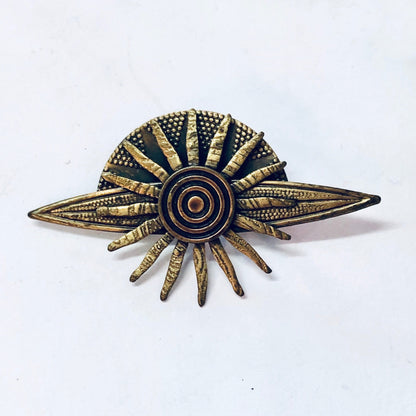 Vintage brass-toned sun brooch with intricate textured design resembling a solar system or planet, suitable as a unique costume jewelry gift idea.