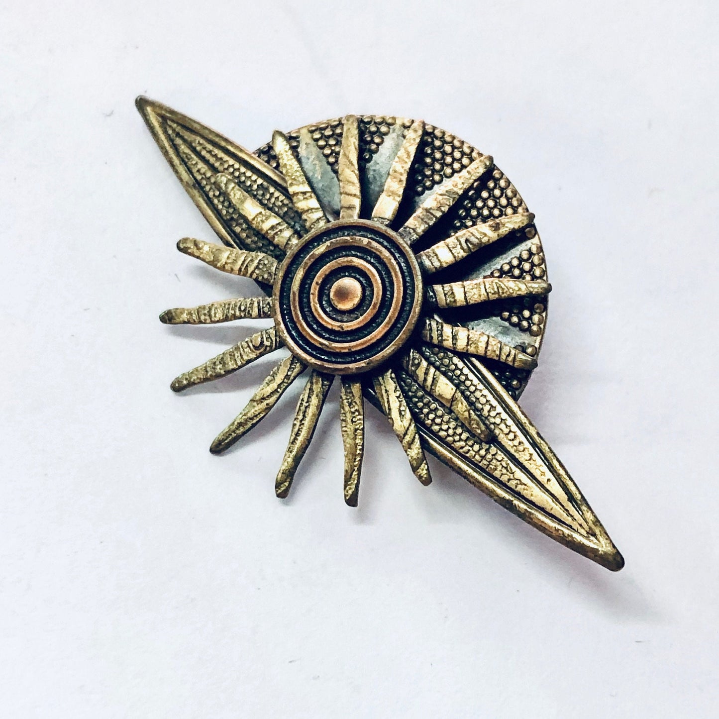 Vintage brass-toned sun-shaped brooch or pin with radiating textured rays, resembling planet jewelry or celestial costume jewelry from the solar system. Unique gift idea from vintage collection.