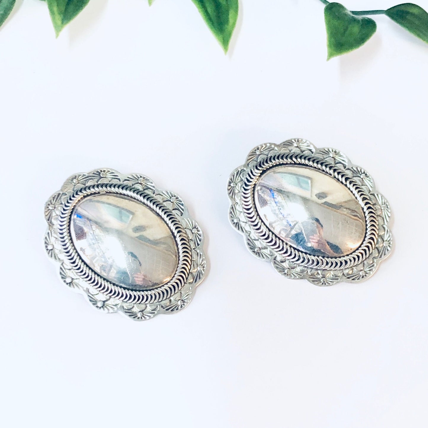 Vintage silver concho clip-on earrings with unique Taxco 925 design set against green leaves